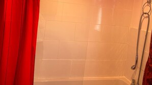 Ein Duschbereich mit Glasabtrennung, einer weißen Fliesenwand und einem roten Vorhang.