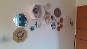A wall with various decorative items including a hexagonal mirror, a clock, and a sign with the text "Make Things Happen".