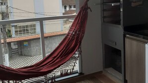 A balcony with a red hammock, a view of buildings, and a Harley-Davidson sign.