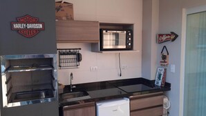 A compact kitchen with a built-in oven, microwave, and a coffee machine.