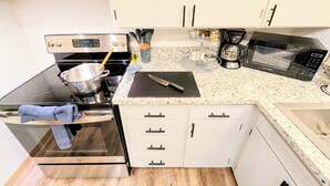 A compact kitchen with a stove, oven, microwave, and coffee maker. - Bright 2BR, Cal King Bed, 15 Min walk to OSU (Corvallis)
