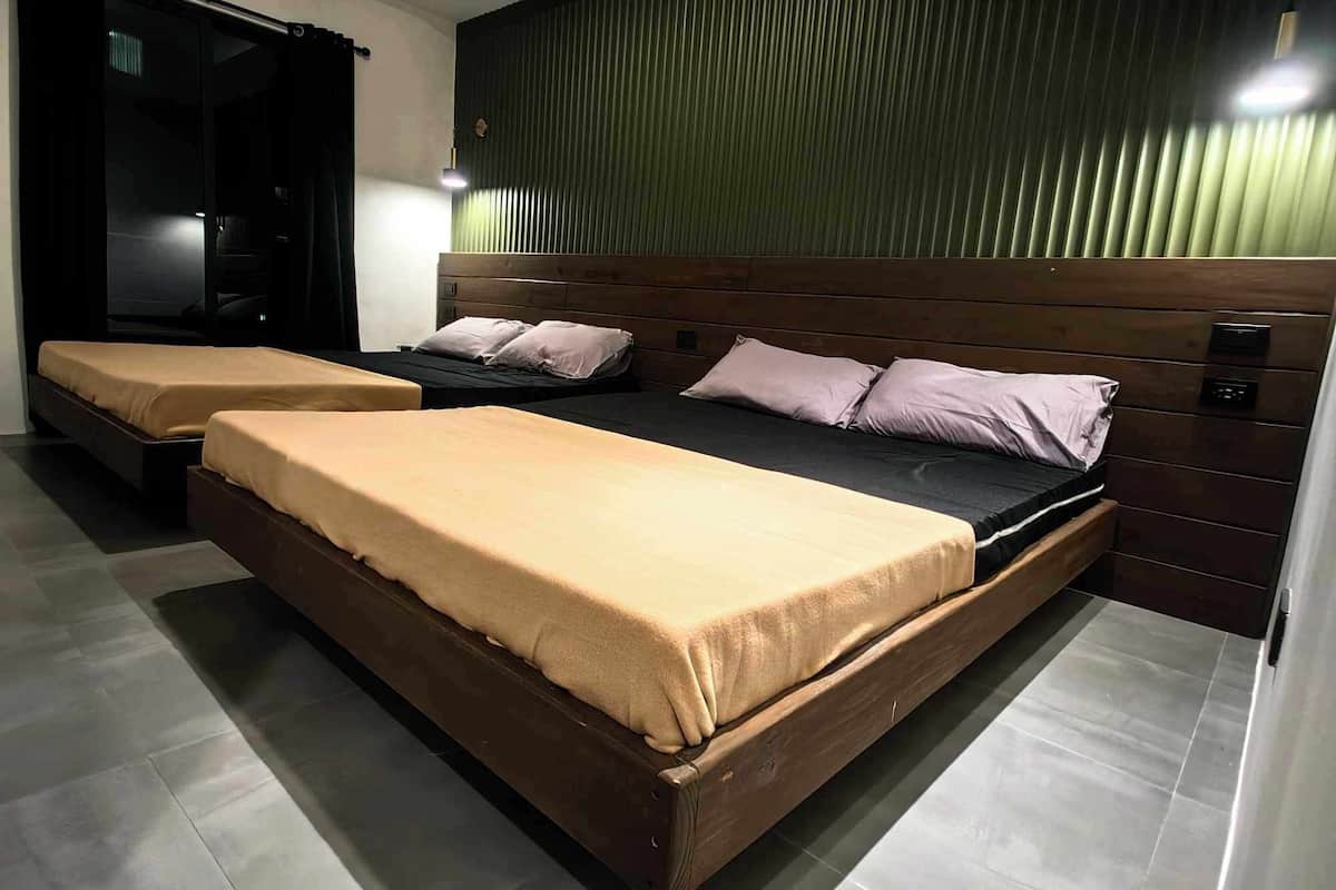 A modern hotel room with two single beds, a wooden headboard, and a large window with blinds.