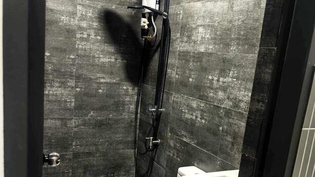 A modern bathroom with a shower, toilet, and sink. - RA House Residences (Makati)