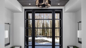 A modern interior with a wooden ceiling, a large glass door leading to a snowy outdoor area, and a grey rug on the floor. - 6 Bedroom Ski In/Ski Out Luxury 6 Bedroom Private Gated Community (Park City)
