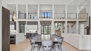 A spacious, multi-level living area with a large dining table, modern furniture, and a staircase connecting the levels. - 6 Bedroom Ski In/Ski Out Luxury 6 Bedroom Private Gated Community (Park City)