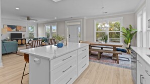 Una cocina amplia con una isla grande, suelo de madera y un comedor con banco y mesa.