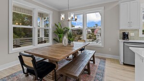 Un comedor con mesa de madera, bancos y sillas. Amplias ventanas con vistas al exterior.