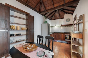 A kitchen with wooden cabinets, a refrigerator, and a dining table with chairs.