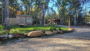 Un terrain de camping doté de cabanes en bois, d’une table de pique-nique et d’un petit bâtiment surmonté d’un mât pour drapeau.