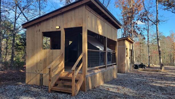 Une cabane en bois avec un escalier menant à une véranda couverte.