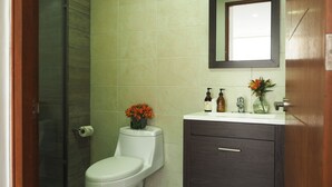 A bathroom with a toilet, a shower, and a vanity with toiletries.
