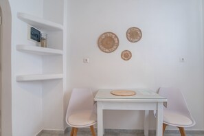 A white room with a table, two chairs, and three woven wall decorations.
