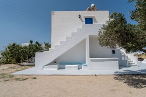A white building with a blue door, a staircase, and a small window.