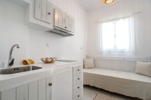 A modern kitchen with a built-in sink, white cabinets, and a window with sheer curtains.