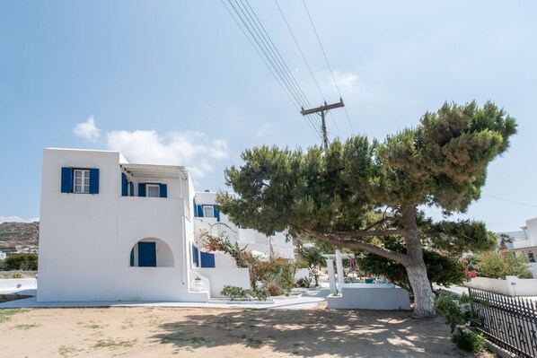 Un edificio blanco con detalles azules, un árbol y un cielo despejado.