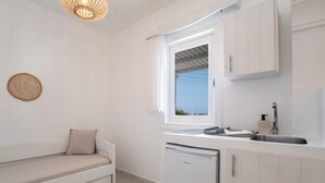 A compact kitchenette with a built-in dishwasher, a window with a view, and a white sofa with a cushion.