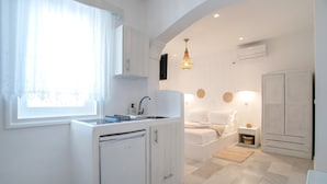 A modern kitchen with a dishwasher, a sink, and a window with sheer curtains.