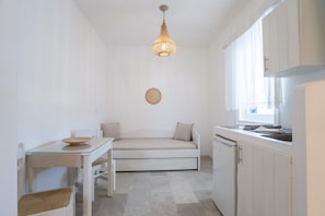 Una cocina compacta con comedor, un sofá integrado y una lámpara colgante.