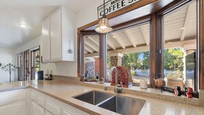 A kitchen with a double sink, white cabinets, and a coffee sign above the sink. - Vineyard Vista Retreat– Your Serene Getaway in Temecula (Temecula)