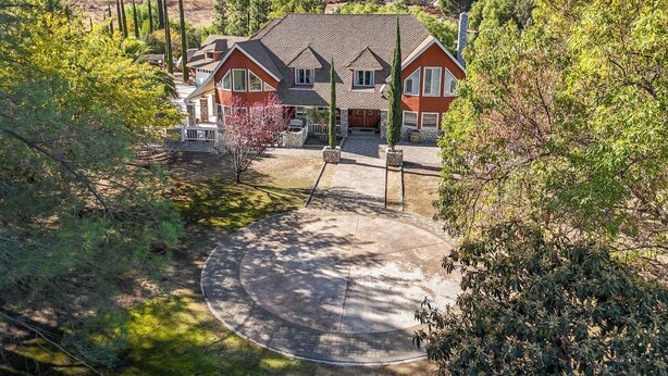 A two-story house with a brick facade, a front porch, and a driveway leading to a circular driveway. - Vineyard Vista Retreat– Your Serene Getaway in Temecula (Temecula)
