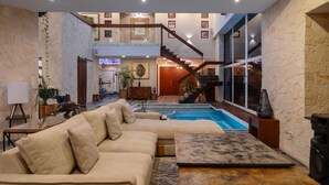Un amplio salón con un sofá beige grande, una mesa de centro y una piscina.