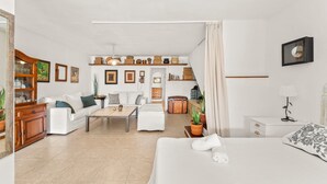 A modern hotel room with a bed, a sofa, a coffee table, and a dining area. - Holiday Home 'Casa Princesa Guayarmina 49' with Private Terrace, Garden & Wi-Fi (Puerto del Carmen)