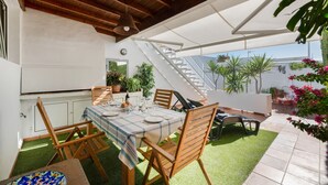 An outdoor dining area with a table set for four, surrounded by wooden chairs, a staircase, and potted plants. - Holiday Home 'Casa Princesa Guayarmina 49' with Private Terrace, Garden & Wi-Fi (Puerto del Carmen)