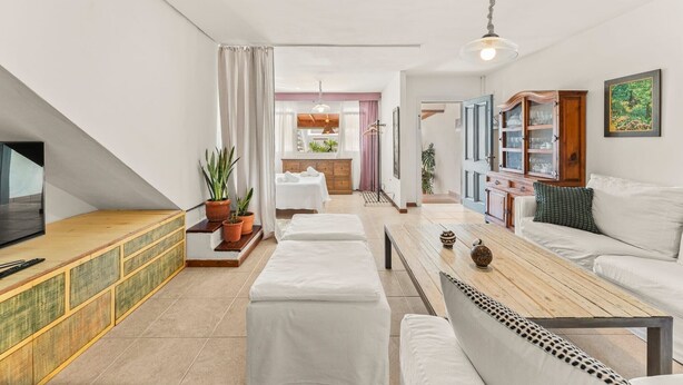 A modern living room with a TV, sofa, ottoman, and a dining area with a table and chairs. - Holiday Home 'Casa Princesa Guayarmina 49' with Private Terrace, Garden & Wi-Fi (Puerto del Carmen)
