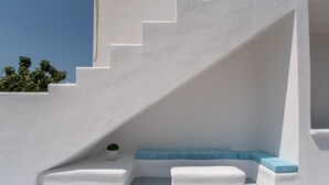 A white staircase with a blue bench and a potted plant.