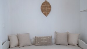 Ein weißes Sofa mit beige farbenen Kissen und einer gewebten Wanddeko.