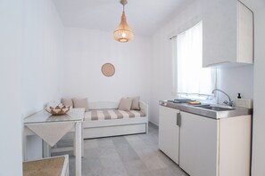 A compact kitchen with a dining area, a bed, and a hanging light fixture.