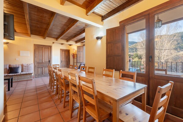 A dining area with a wooden table and chairs, a sofa, and a view of the outdoors.