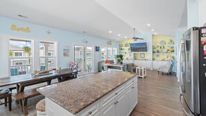 Una cocina amplia con encimera de granito, muebles blancos y un refrigerador de acero inoxidable.