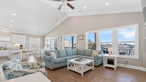 A spacious living area with a high ceiling, a dining set, and a view of the outside. - "Marina Jack" 5 Bedroom 5 Bath with a Pool! (Holden Beach)