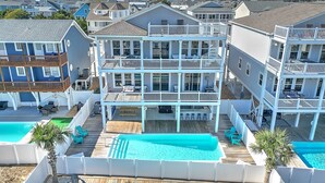 A multi-story residential building with a pool and outdoor seating area. - "Marina Jack" 5 Bedroom 5 Bath with a Pool! (Holden Beach)