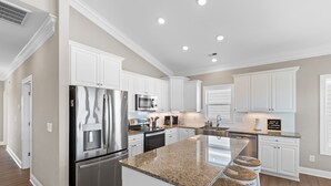 A modern kitchen with white cabinetry, stainless steel appliances, and a granite countertop. - "Marina Jack" 5 Bedroom 5 Bath with a Pool! (Holden Beach)