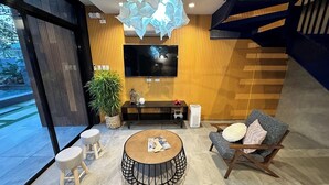 A modern living room with a round coffee table, a sofa, a TV, and a staircase. - Fabulous 3-bedroom Private Villa in Lubao Pampanga with plunge pool (Lubao Pampanga)