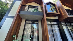 A modern two-story building with a wooden facade, large windows, and a balcony with green railings. - Fabulous 3-bedroom Private Villa in Lubao Pampanga with plunge pool (Lubao Pampanga)