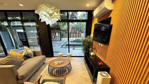 A modern living room with a sofa, coffee table, and chairs, a large TV, and a view through large windows. - Fabulous 3-bedroom Private Villa in Lubao Pampanga with plunge pool (Lubao Pampanga)