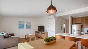 Un salon moderne comprenant un canapé, une table basse, un téléviseur et un coin repas avec une table et des chaises.