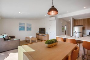 Un salon moderne comprenant un canapé, une table basse, un téléviseur et un coin repas avec une table et des chaises.