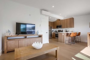 Uma cozinha moderna com armários de madeira, micro-ondas embutido e uma ilha central com banquetas.