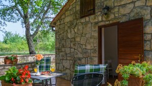 A stone building with a patio area featuring a table with a drink, chairs, and potted plants. - Villa Martina (Istria - Labin) (Šumber)