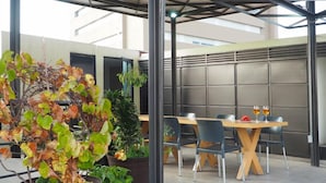 Een terras buiten met een tafel en stoelen, omringd door potplanten.