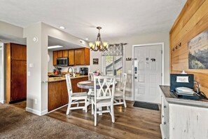 A kitchen with wooden cabinets, a microwave, and a chandelier.