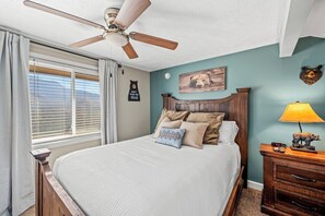 A bedroom with a bed, a ceiling fan, a nightstand, a lamp, and a wall clock. - Sleeps 6 Mountain Views Shared Resort Amenities (Gatlinburg)