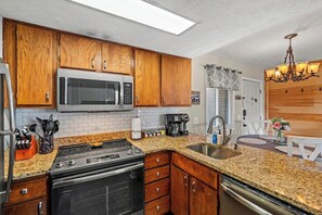 A kitchen with wooden cabinets, a stainless steel microwave, a gas stove, and a dishwasher. - Sleeps 6 Mountain Views Shared Resort Amenities (Gatlinburg)