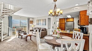 A modern living room with a dining area, a kitchen, and a staircase leading to a balcony. - Sleeps 6 Mountain Views Shared Resort Amenities (Gatlinburg)