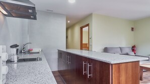 Uma cozinha com bancada de granito, armários de madeira e um exaustor de aço inoxidável.