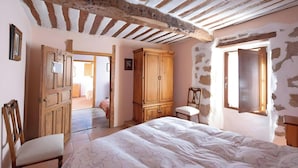 Een slaapkamer met een bed, een houten garderobe en een stoel.